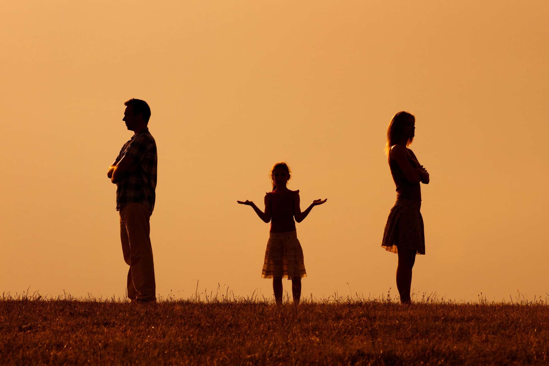 Silhouet van een man en een vrouw die apart staan met hun armen over elkaar, met hun gezicht van elkaar af, terwijl een kind tussen hen in staat met zijn armen omhoog in een vragend gebaar. Dit alles tegen een oranje achtergrond.